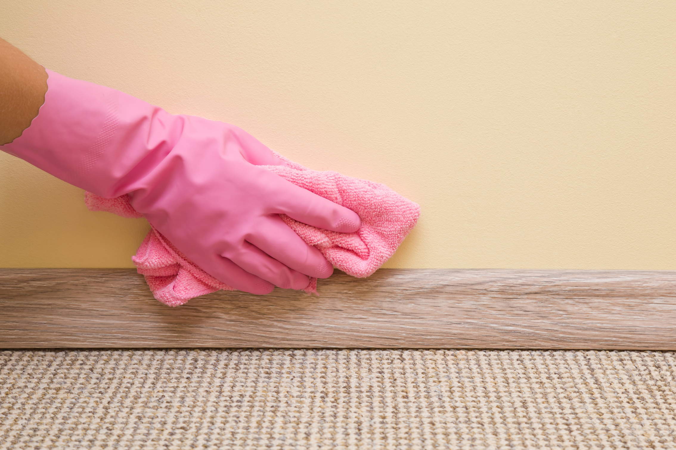 A gloved hand cleaning a wall prior to painting